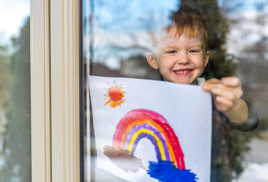 Junge hängt Regenbogen ins Fenster